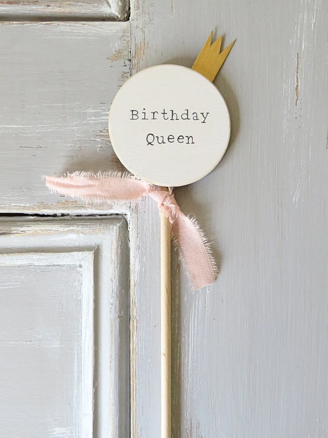 wooden circle shaped cake topper with hand painted message, gold painted crown detail and custom ribbon