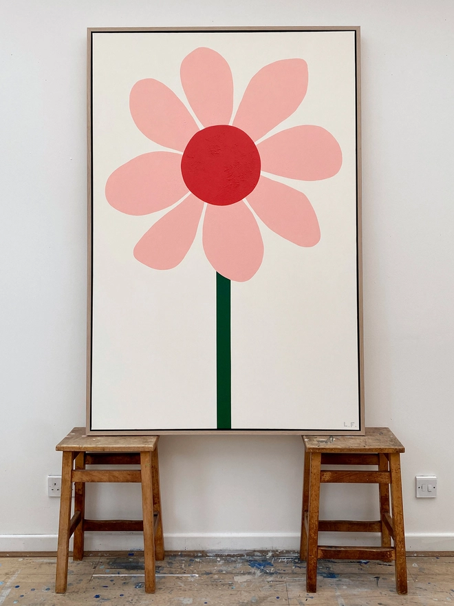 Giant pink and red painting of a flower on top of wooden stools