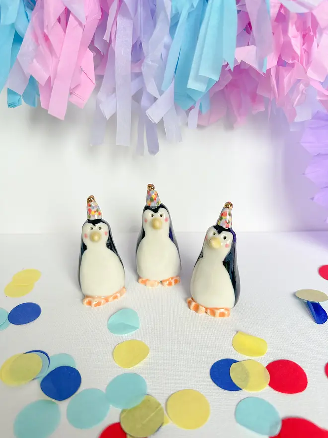 Handmade Porcelain Party Penguin Topper, grouped together near party decorations. 