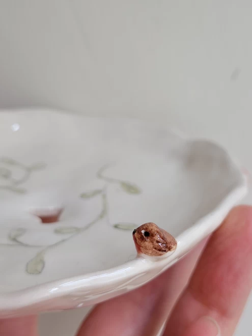 close up of tiny robin red breast bird detail on a white ceramic soap dish