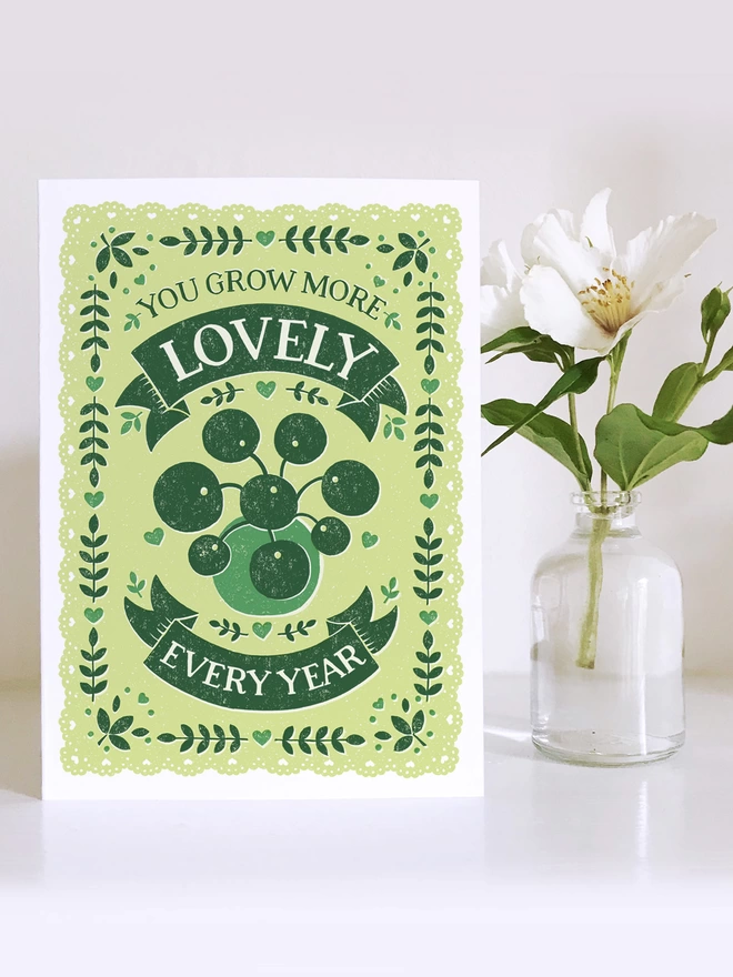green chinese money plant birthday card with white flower in a small vase