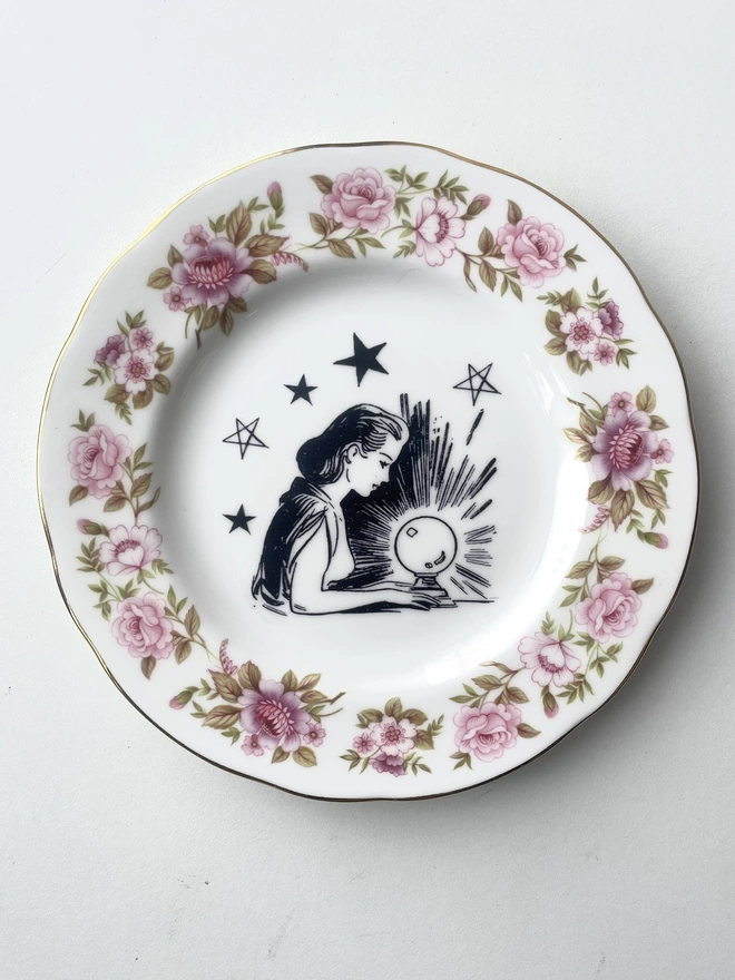 a vintage ornate plate with a pink floral border detail, in the centre i have printed a vintage black and white illustration of a pretty fortune teller reading a crystal ball