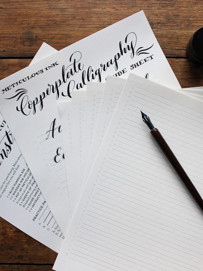 Meticulous Ink Copperplate Calligraphy Kit - Guidsheets, practice paper and nib holder on wooden table