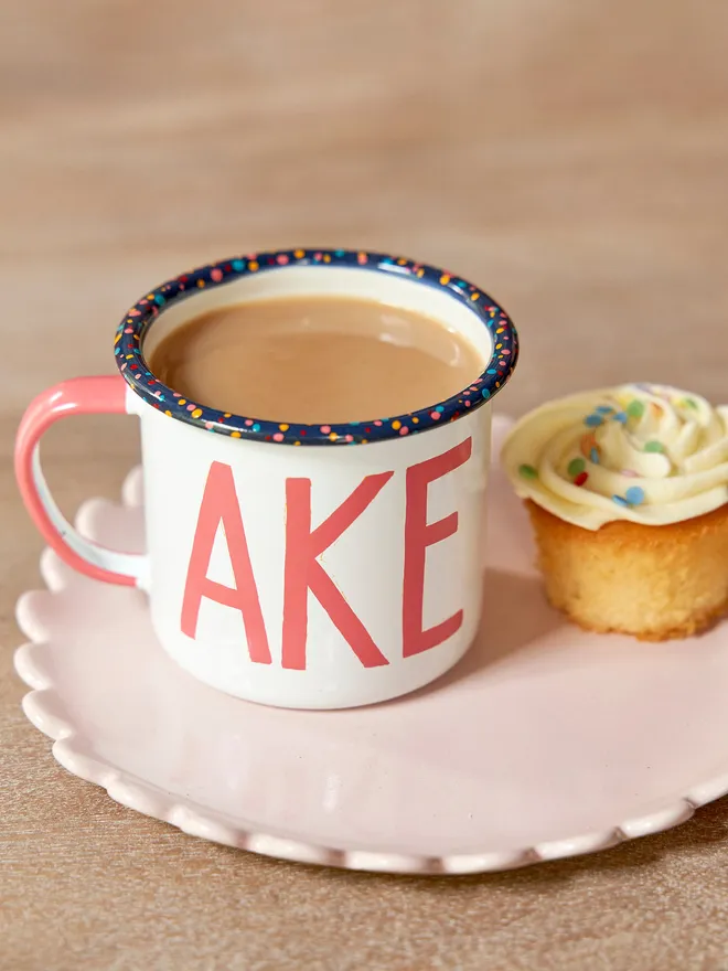 white mug with pink 'cake' text and paint splatter rim
