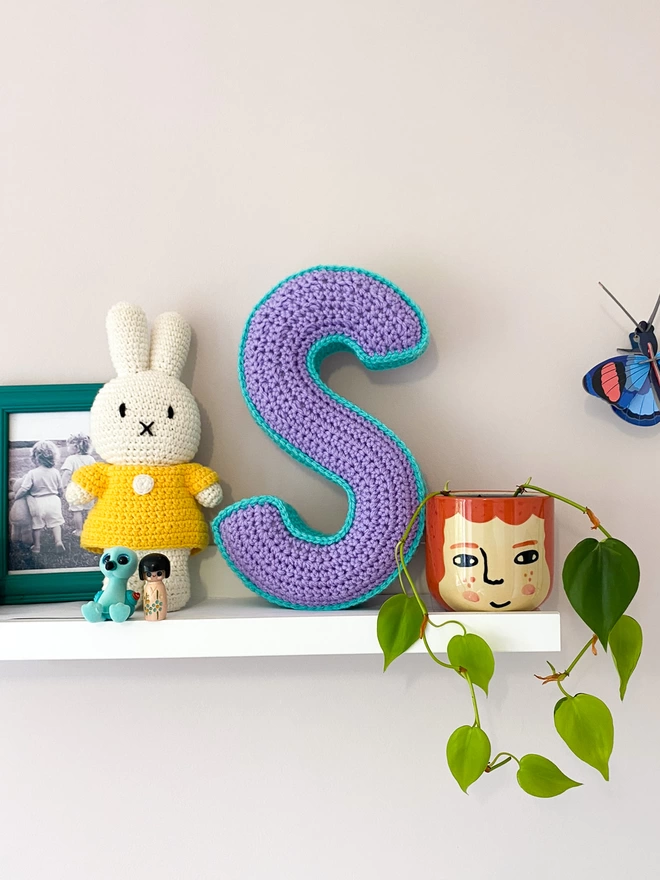 Crochet Cushion shaped like an S on a child's shelf