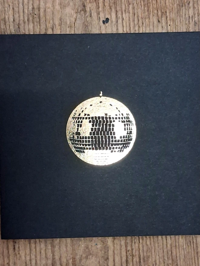 A greetings card printed in gold foil on black card with a picture of a disco ball