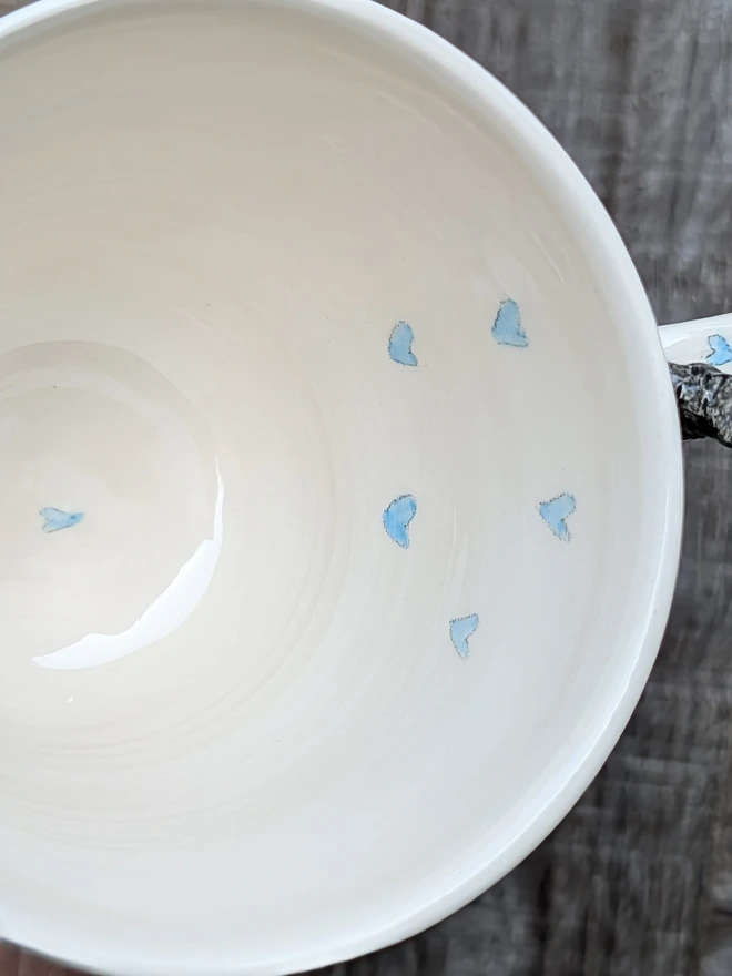 the inside of a personalised dog mug with a tiny dog on the handle, showing blue hearts inside the mug