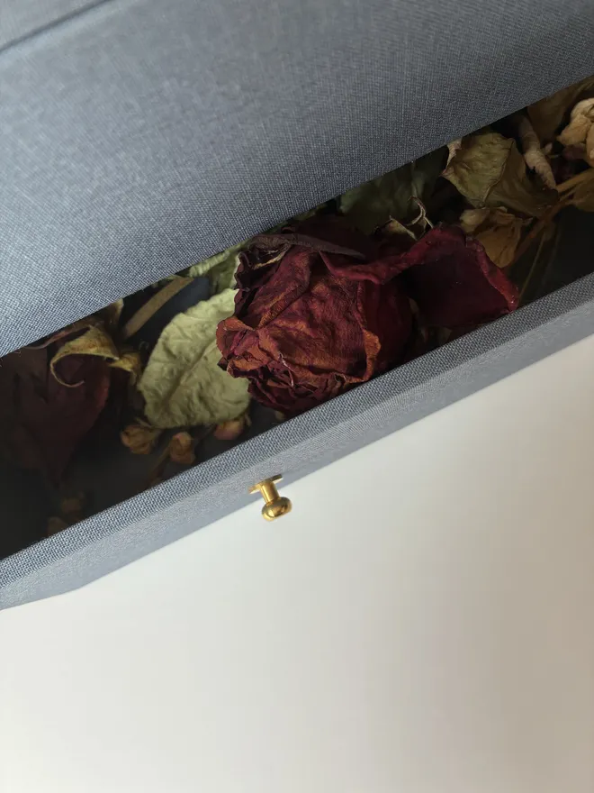 Close up detail of the open drawer of a handmade wedding keepsake box in Steel Blue housing a dried wedding bouquet