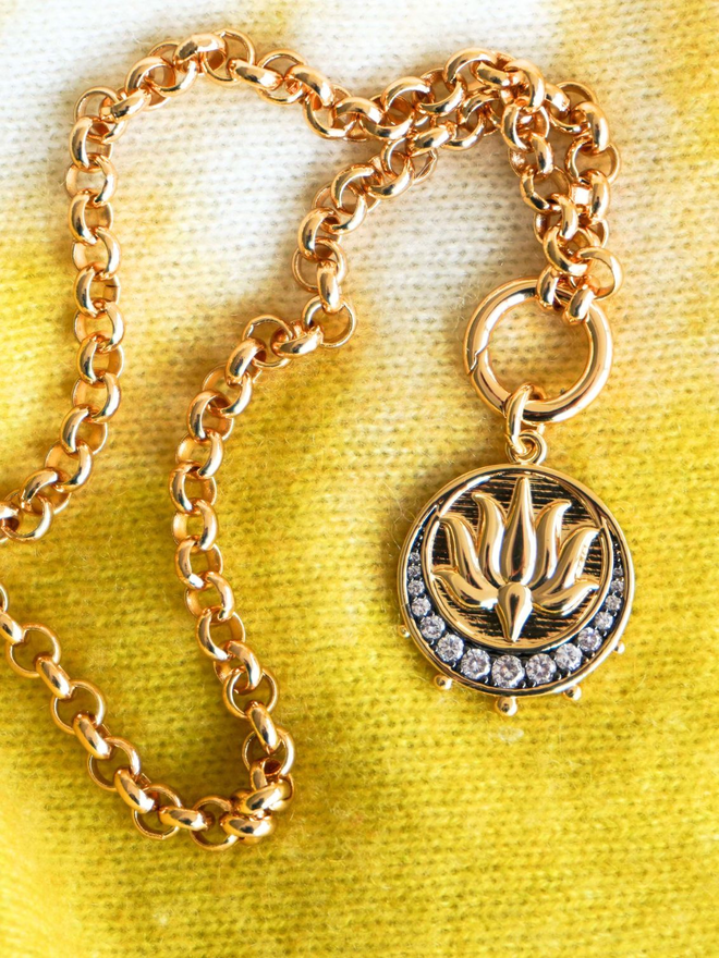 Gold lotus medallion charm inside a gold dish on yellow cashmere background