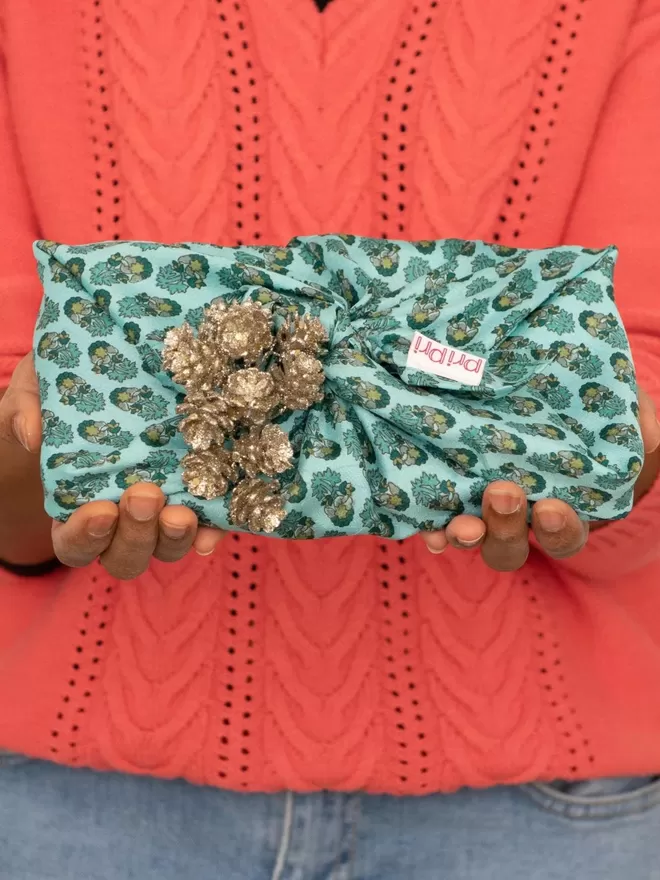 blue and green wrap gift with a gold decoration