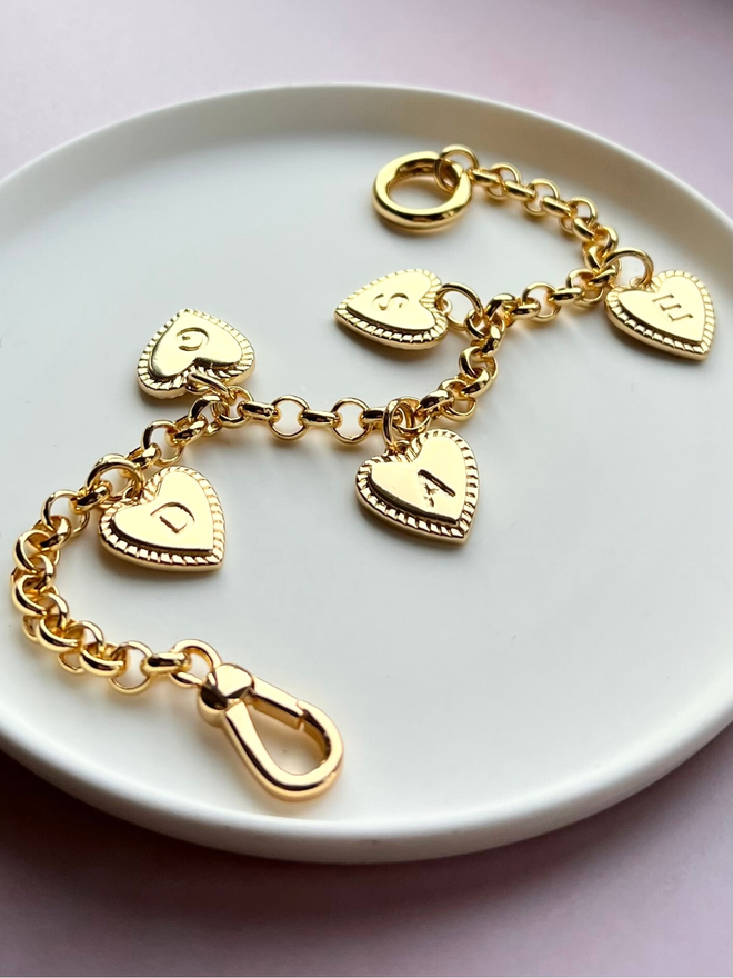 gold belcher chain bracelet with gold heart initial charms on white plate 