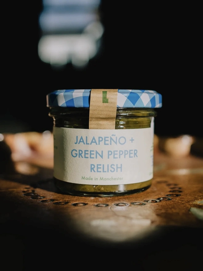 Jar Of Jalapeño & Green Pepper Relish, jar of relish with a blue lid on a decorated plate. 