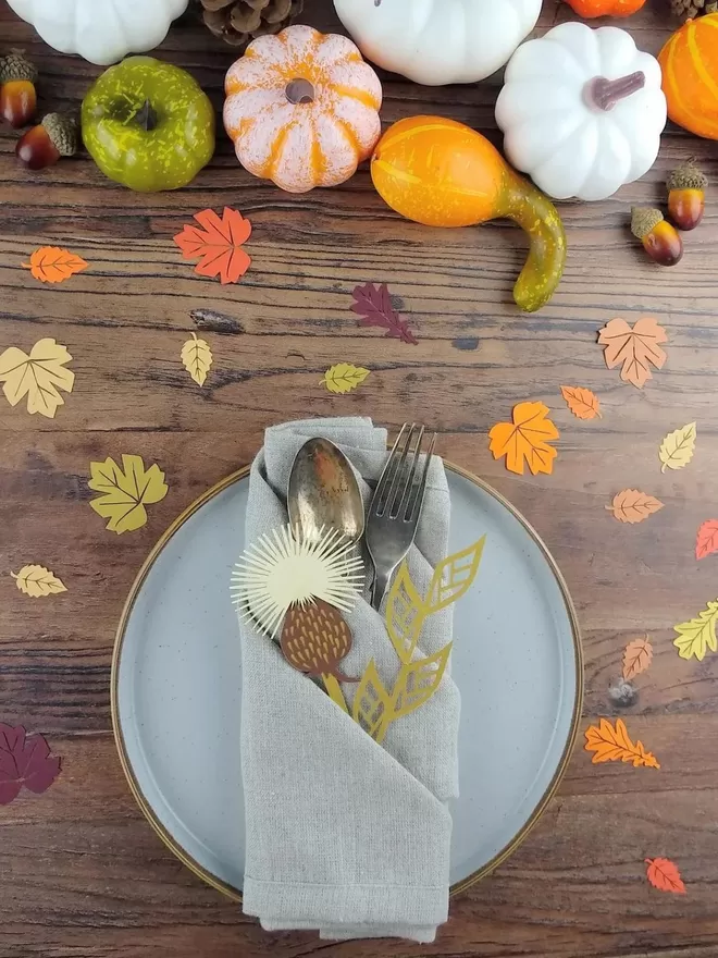 Autumn Leaf Confetti scattered across a wden table with harvest foliage place setting