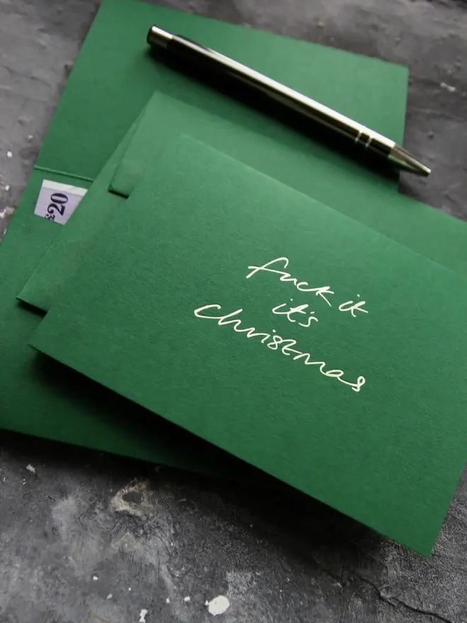 Hand foiled cash card or money wallet in a forest green colour handfoiled in shiny lime green text which says 'fuck it it's christmas'.