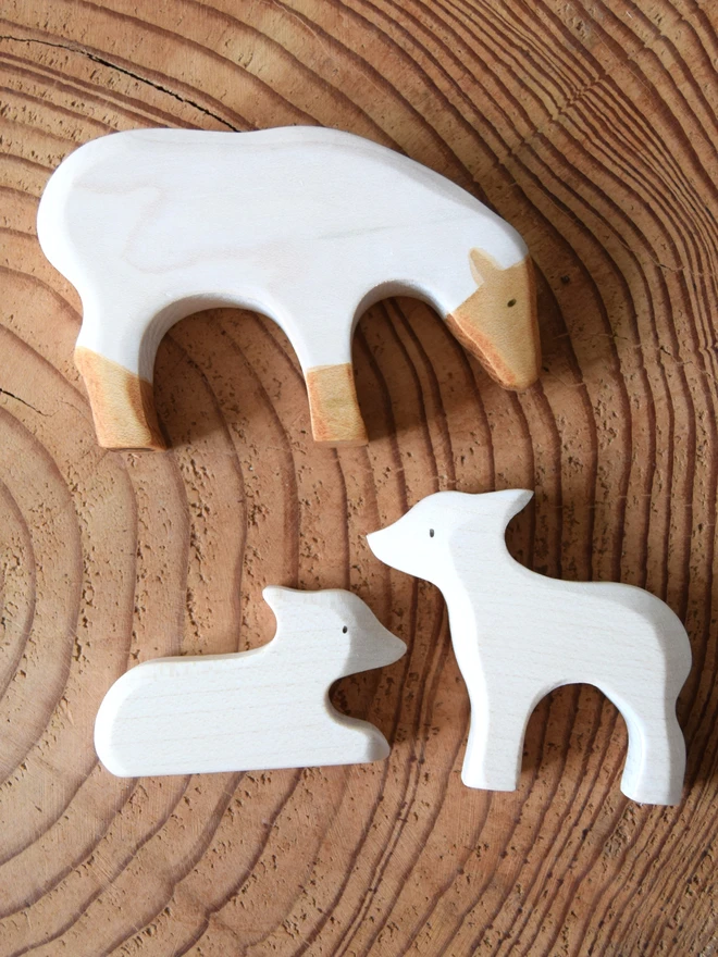 white sheep and lamb bundle of wooden toys on log slice