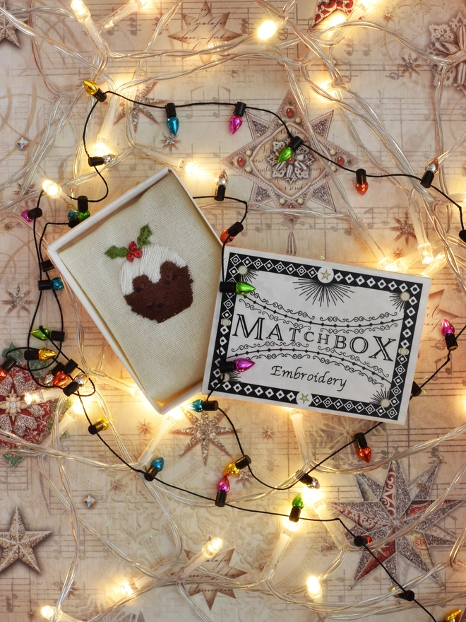 A Classic Christmas Pudding embroidery.   Displayed in its matchbox with fairy lights and mini bauble trims.