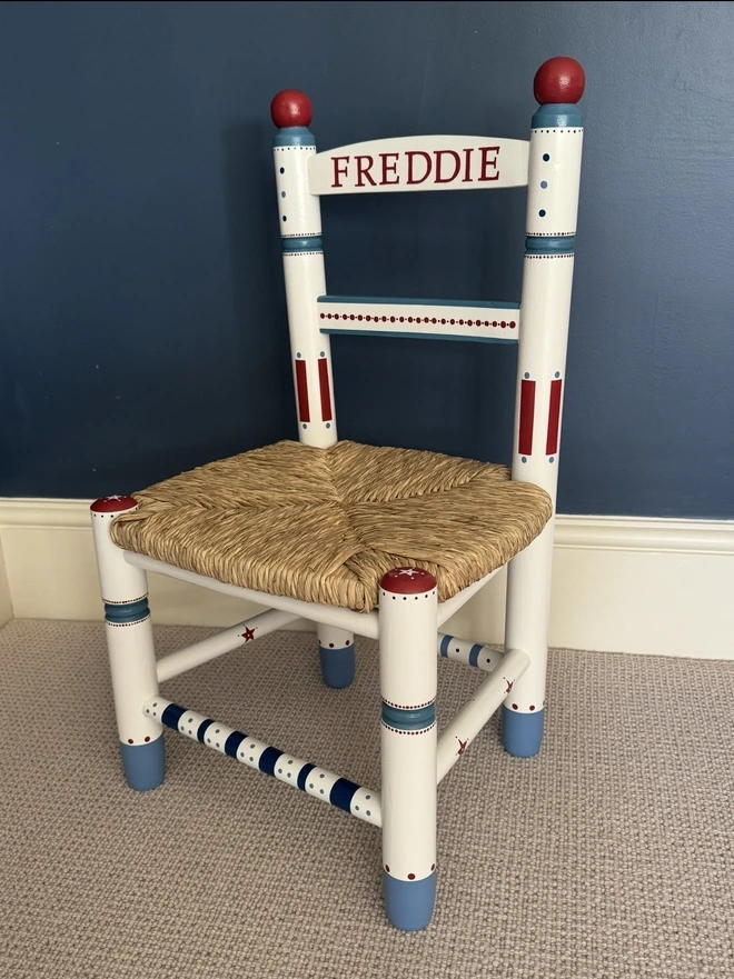 Intricate detail on a Childs wooden rush chair. Red and blue. 