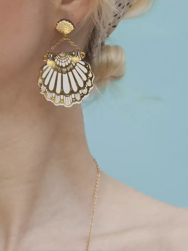 white & gold leather clamshell earrings on model