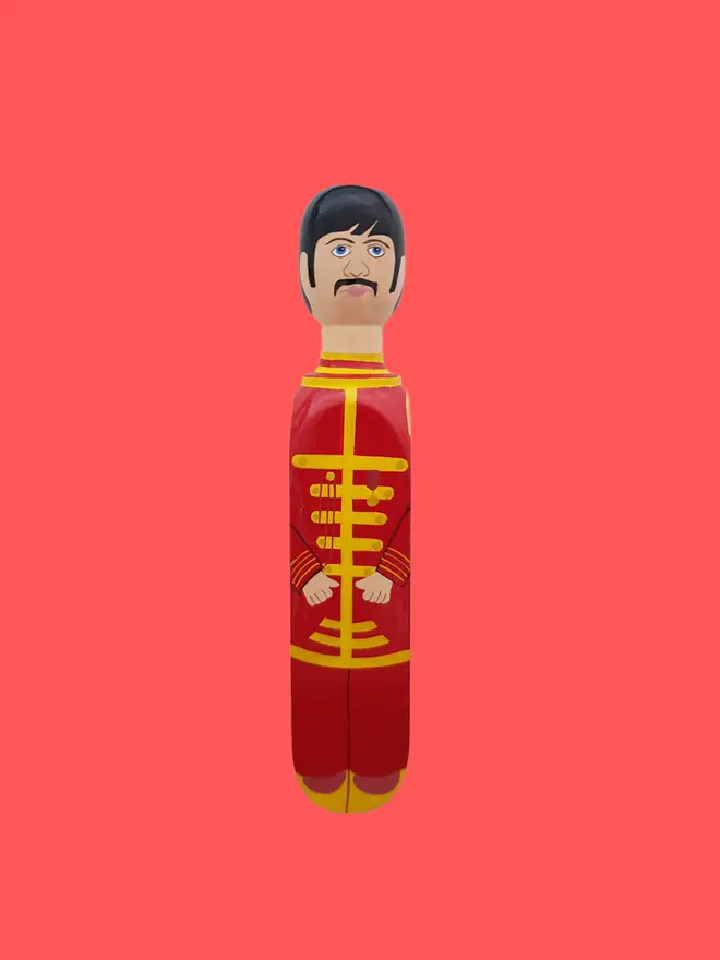 Wooden Door Stopper (Starky), a colourful wooden door stop sitting on a red surface. 