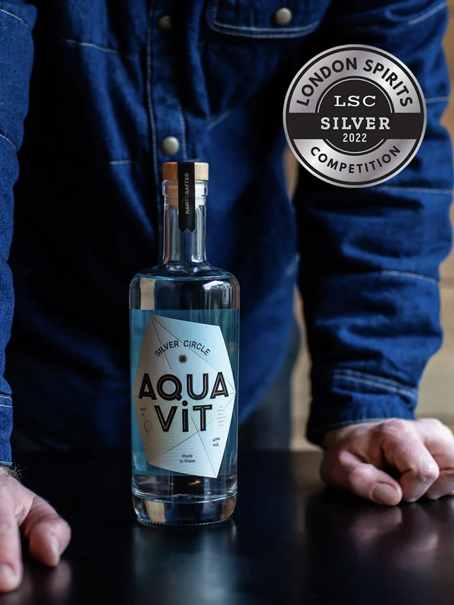 Silver Circle Aquavit, bottle of spirit next to a bartender. 