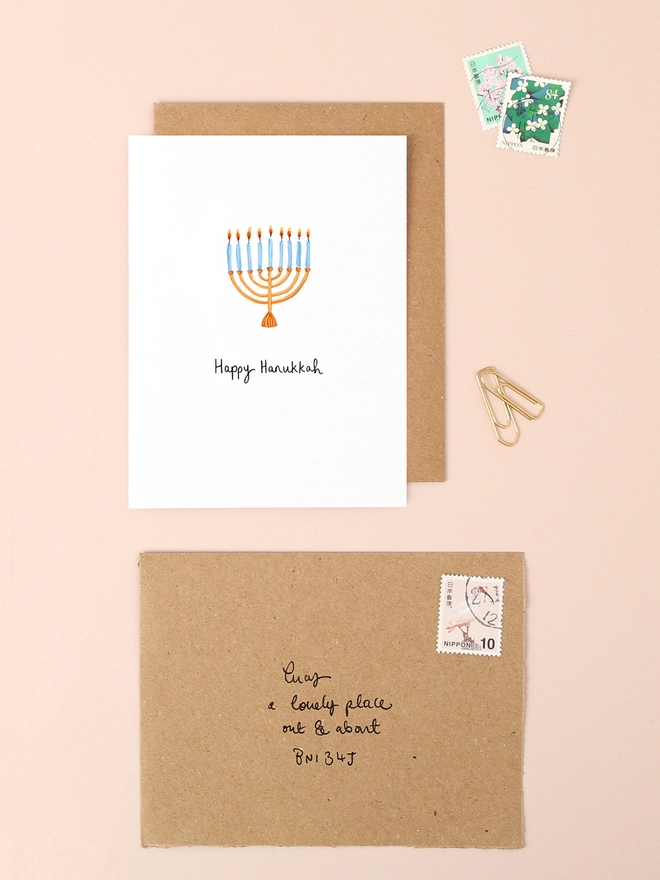 A festive illustration featuring a traditional menorah with nine candles, each glowing warmly. The design captures the essence of Hanukkah, radiating warmth and celebration. The card's compact size and elegant details make it a perfect choice for sending heartfelt holiday greetings.