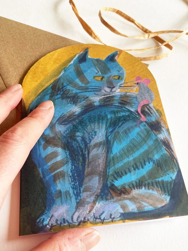 Esther Kent illustrated arch-shaped greeting card showing a blue striped cat looking at a mouse perched on its tail.