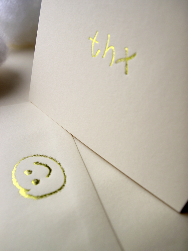 sandy coloured card with thx short for 'thank you' hand foiled in kids hand writing