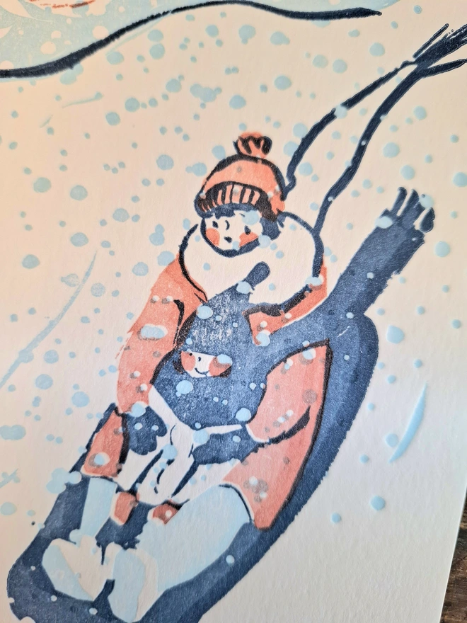 A close-up image of a mother holding her young child as the sledge down a hill in snow, printed in pink, light blue and dark blue.