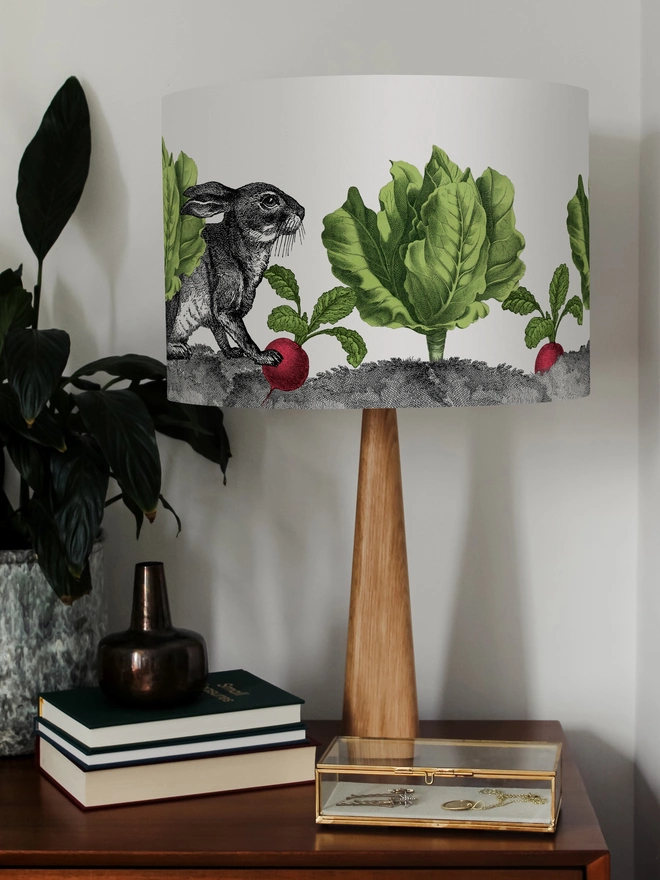 Mischievous rabbit lampshade handmade with vintage animal etchings, hiding among lettuces and radishes in a quirky country-style design. 