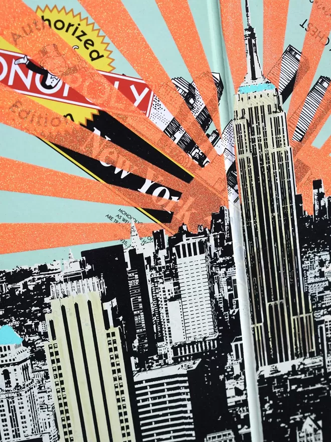 Close crop of a Monopoly Board with New York view printed on top with orange glitter stripes