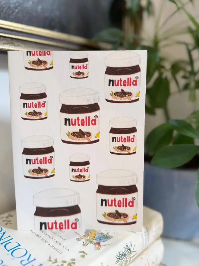 nutella jars illustrated card. card placed on top of book pile on shelf.