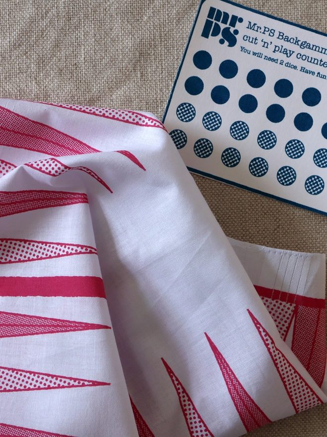 detail of a Mr.PS Backgammon Hankie printed in raspberry with a printed cut-out counter card