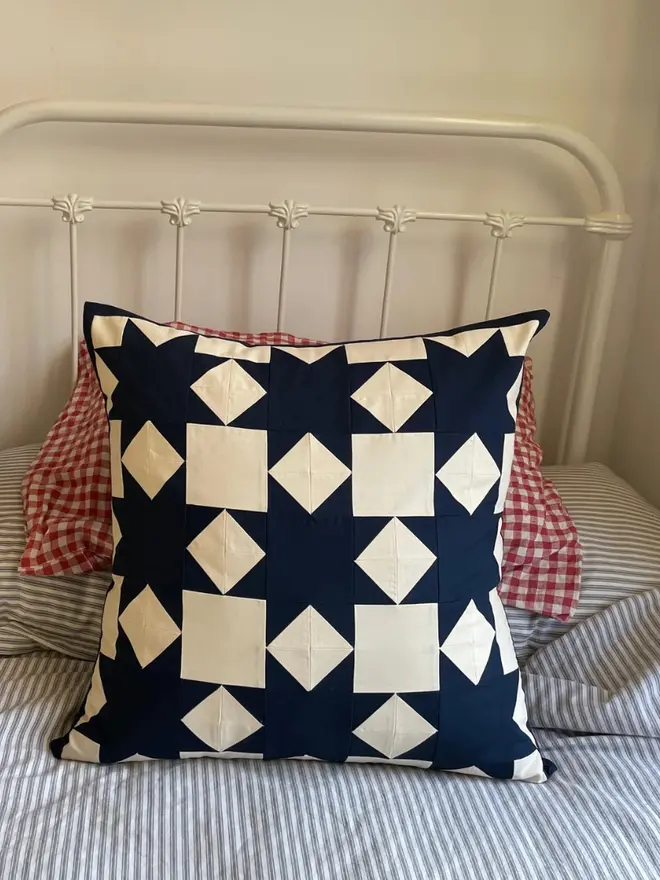 Astrid Patchwork Cushion, on a bed. 