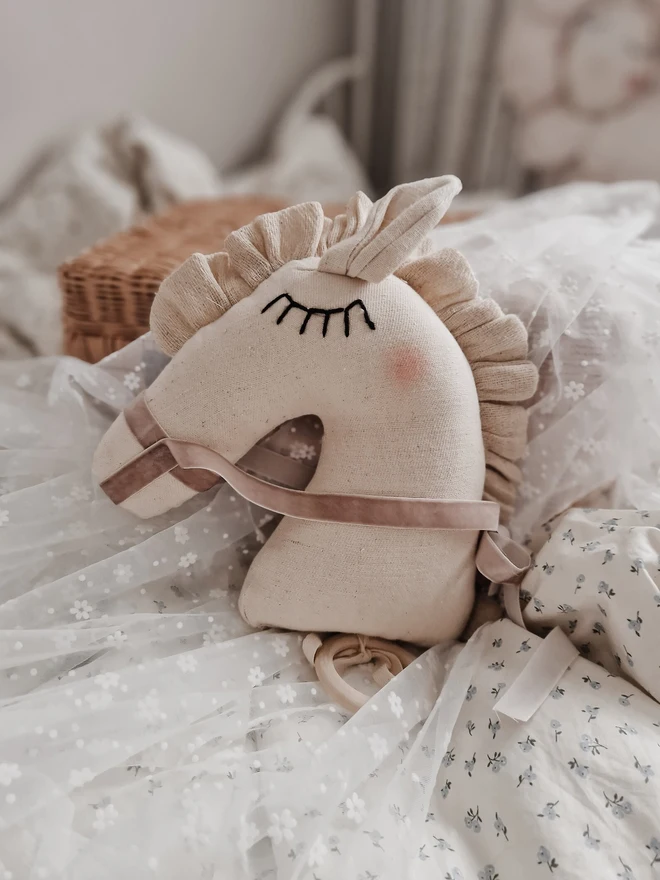 Horse Baby Rattle Toy, a horse rattle toy sitting on a child's bed surrounded by other accessories. 