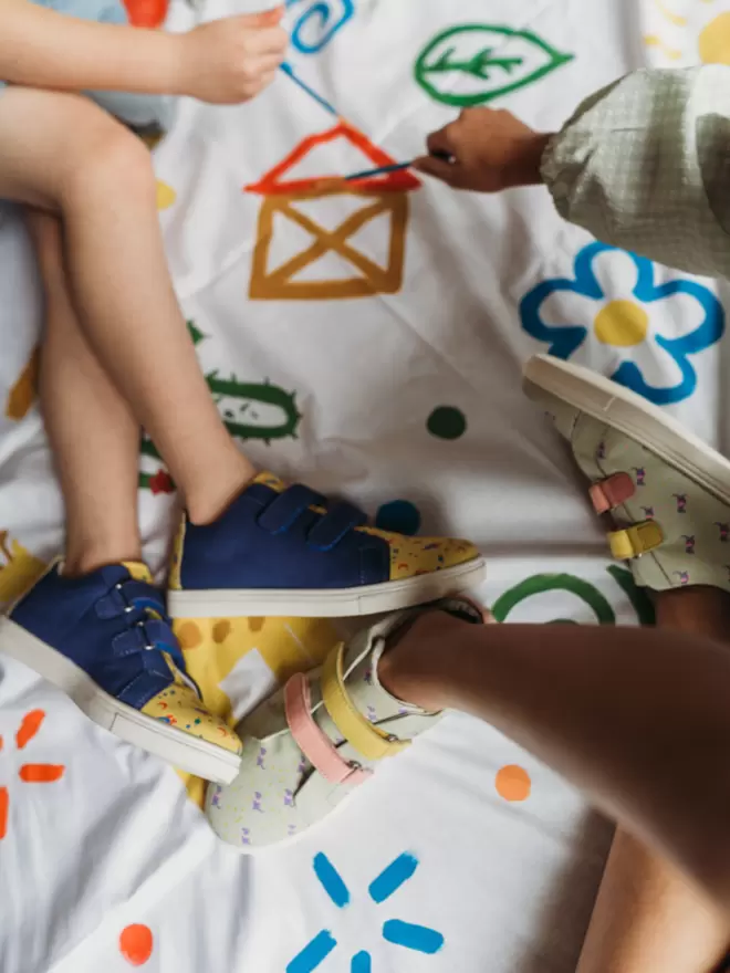 Little boy painting wearing  Pip and Henry blue and h=yellow space print sneaker