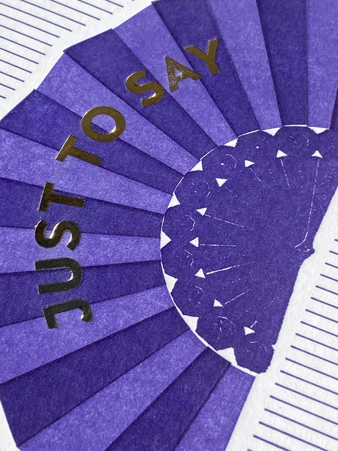Close up of a Purple and white striped card with a purple fan on it and gold text reading 'Just To Say'.