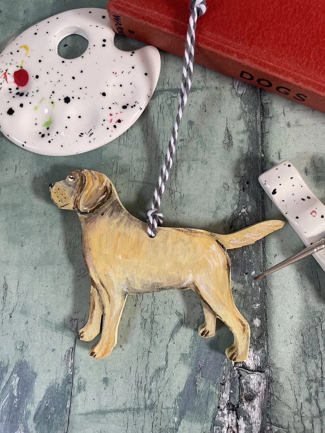 A golden labrador decoration with the art materials used to paint it, around it