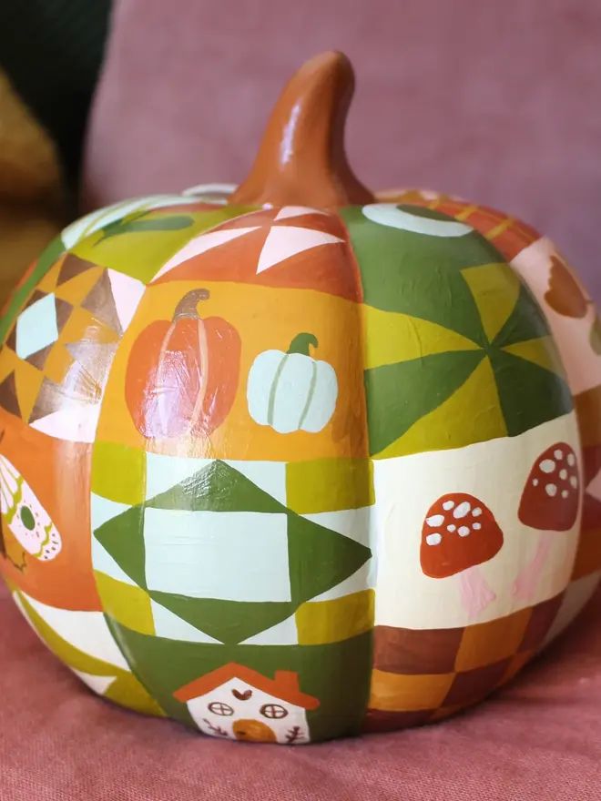 hand-painted woodland ceramic pumpkin. a ceramic pumpkin painted with patchwork colours and patters, alongside mushrooms, moons, stars and flowers.
