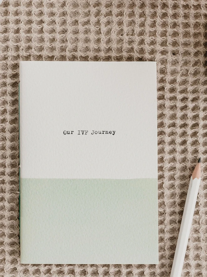 pale green and white notebook with the words 'Our IVF Journey' typed on the cover