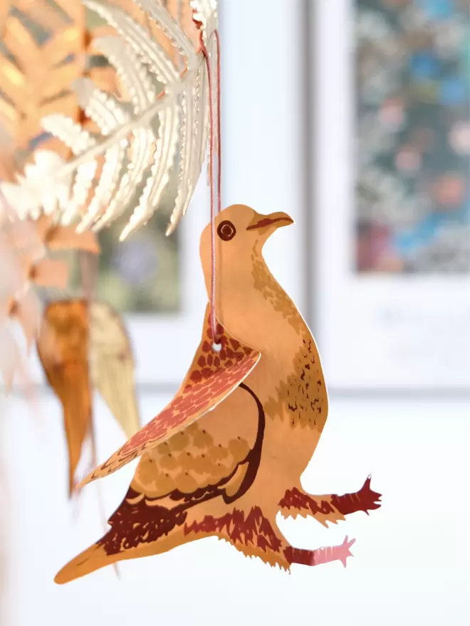 Winter bird hanging from gold lamp, blurred out floral print in background