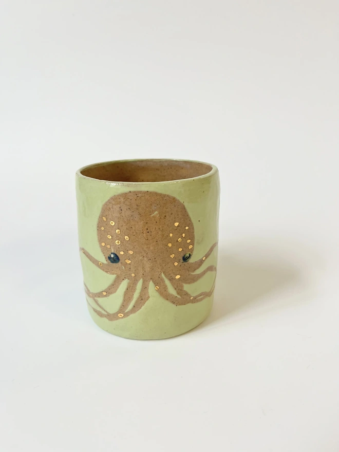 light green octopus mug, with gold detail, image made by scratching through the coloured slip to the natural clay colour underneath and glazing