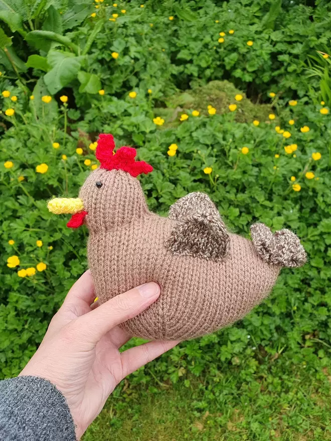 little brown knitted hen in a garden full of buttercups