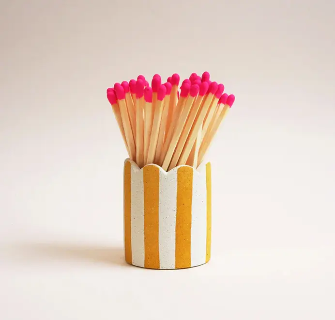 Stripy Match Stick Holders. Coloured matchsticks in a striped, scalloped matchstick holder on a white background.  