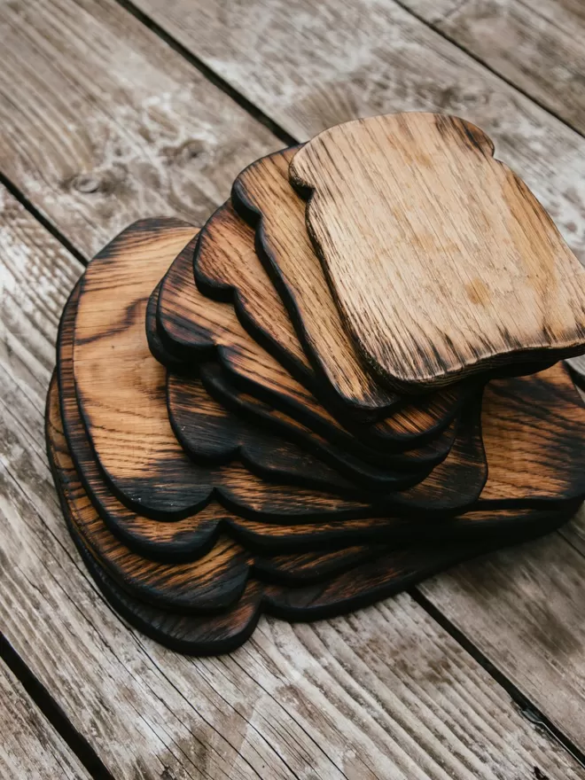 ArtShed ‘That Feeling Of Home!’ Toast Shaped Oak Serving Board seen on a wooden table.