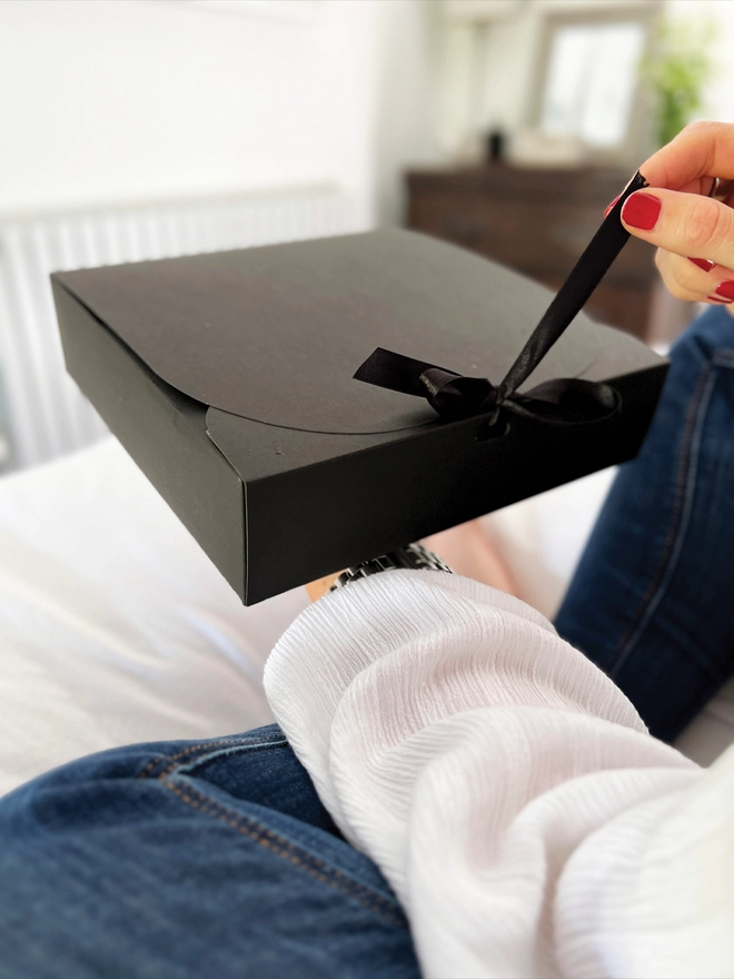 Lady pulling open a black box on the black gift box.