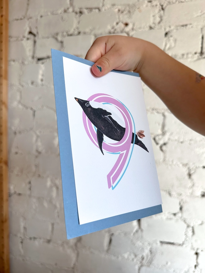 a white card with a big pink number 6 and an illustrated penguin with a blue envelope