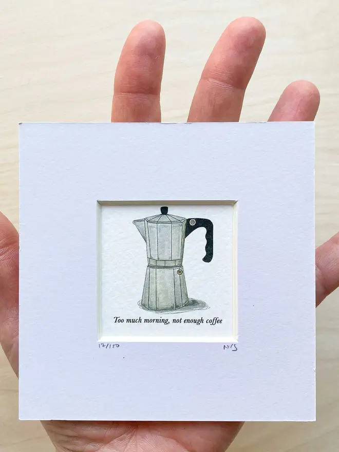 A small art print of a coffee maker framed in a white paper mount, capturing the essence of coffee moments and the art of brewing.