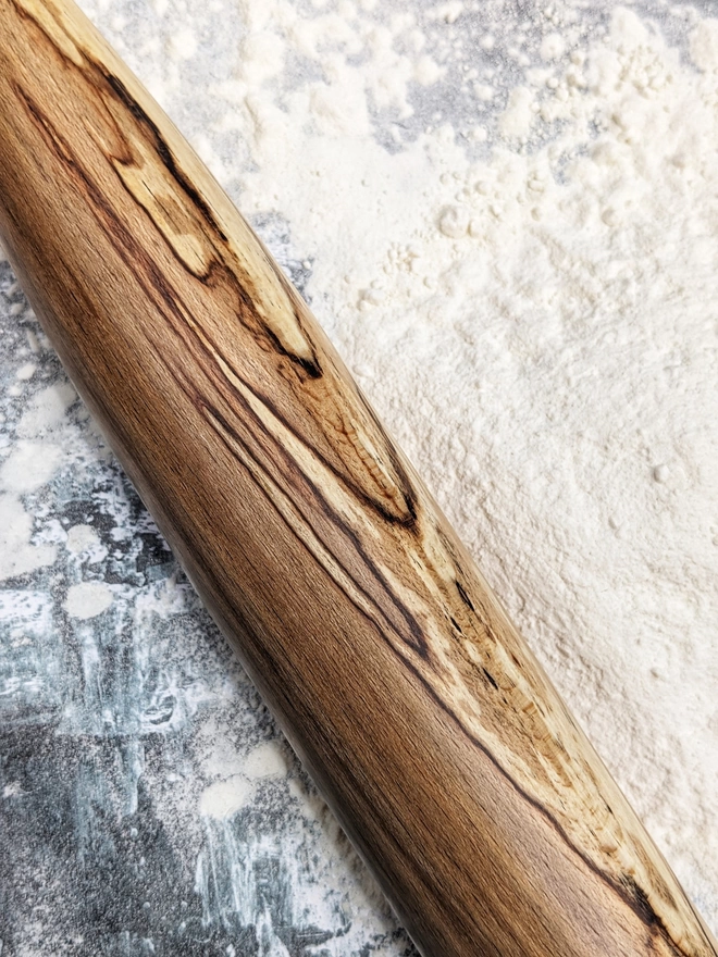 Close up of a stunning hand made rolling pin in Spalted Beech by Something From The Turnery, the picture is focussed on the all natural detailing along the length of the rolling pin.