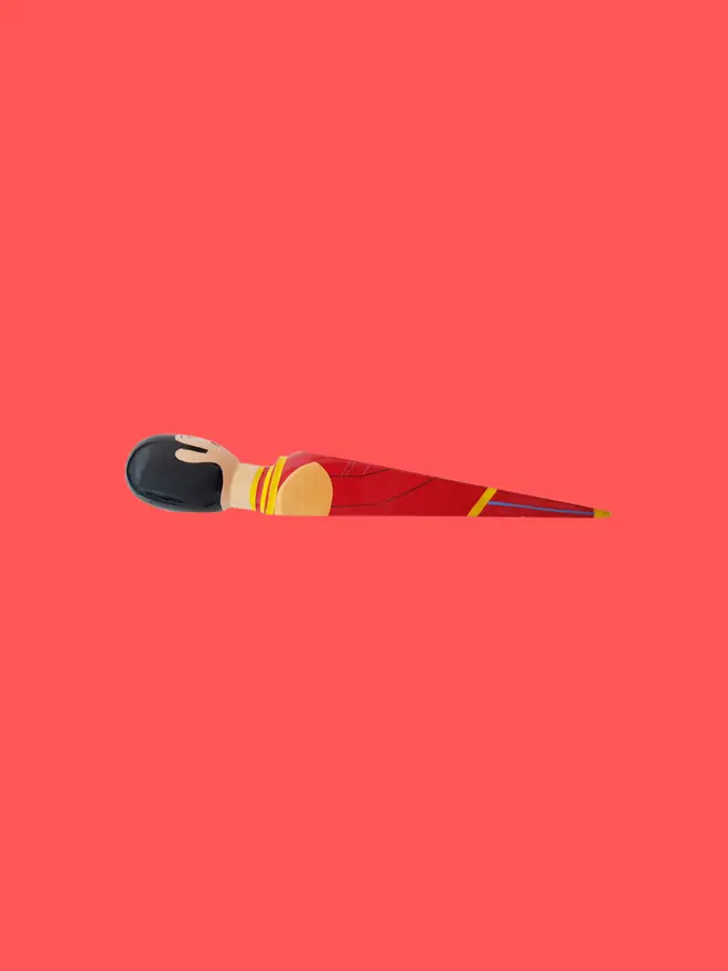 Wooden Door Stopper (Starky), a colourful wooden door stop sitting on a red surface. 