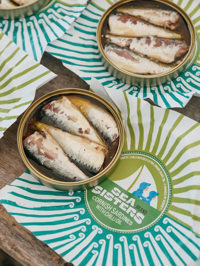 An open tin of Cornish Sardines with Chill Extra Virgin Olive Oil on a table with Sea Sisters napkins